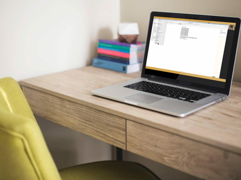 Ordinateur mac dans un bureau avec livre et formation Scrivener mode facile activé affichée sur l'écran